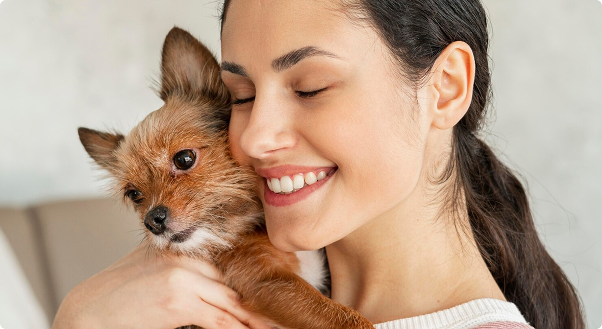 Frau kuschelt mit kleinem Hund – Symbol für eine glückliche Tierbesitzerin
